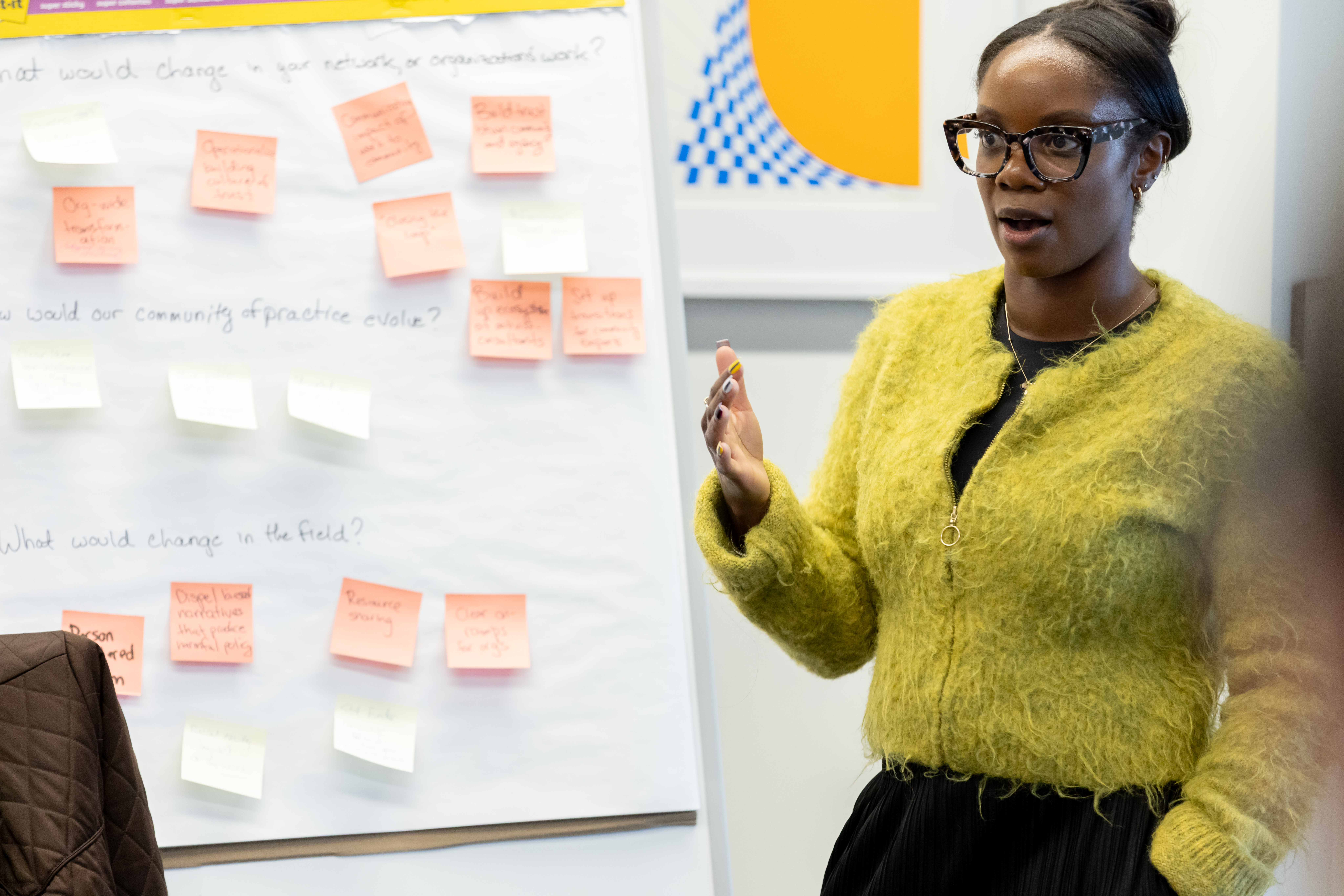 A woman stands before a wall with sticky notes.